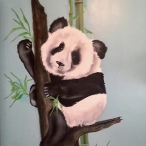 Black and white panda bear in a tree with leaves